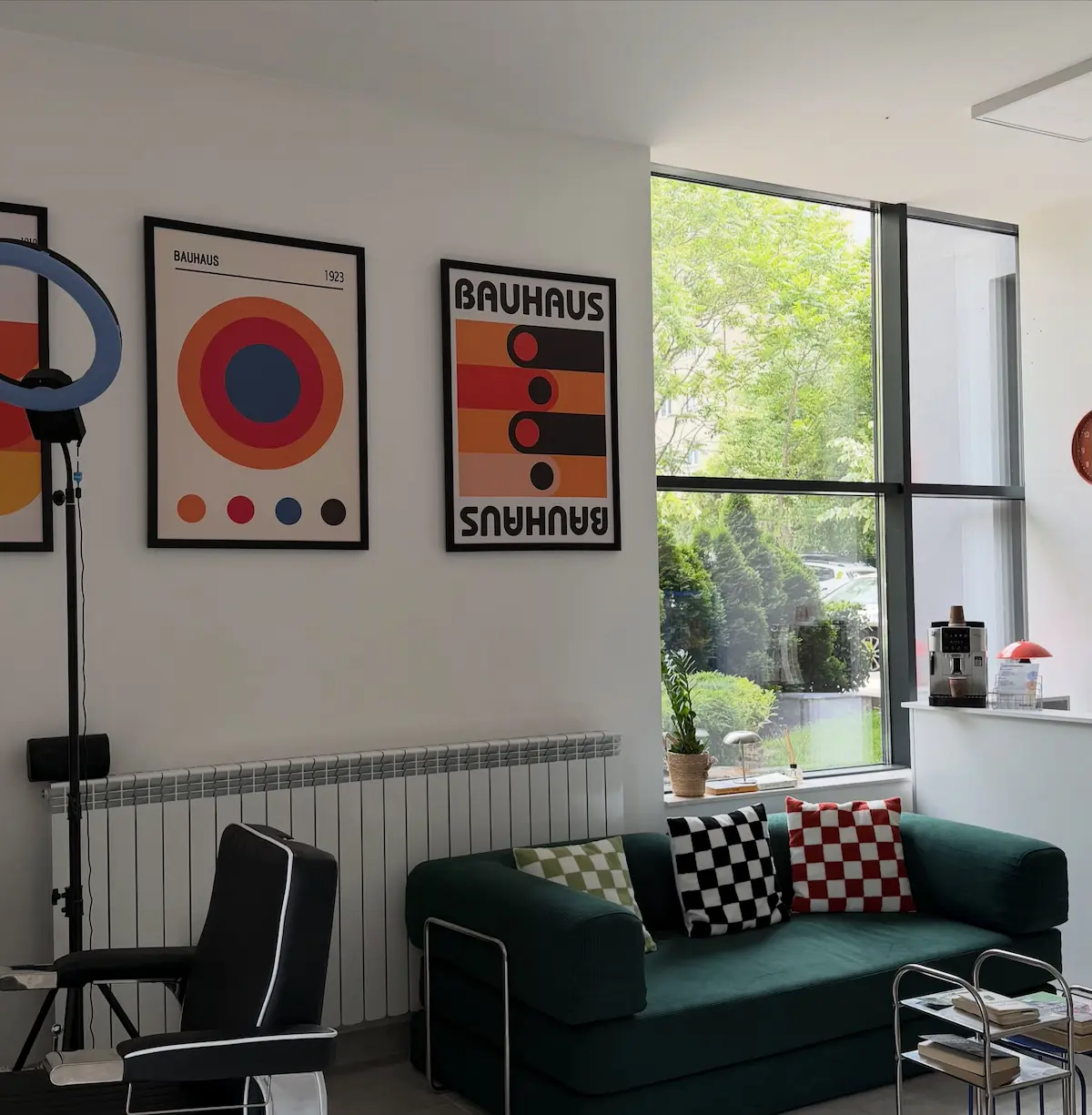 Интериорът на ELEMENT Barbershop — зелен диван и Bauhaus постери до прозореца
